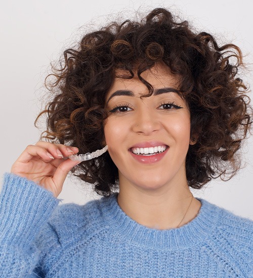 Woman in blue sweater holding a clear aligner
