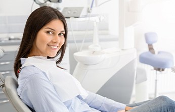 Woman in dental chair looking to side and smiling