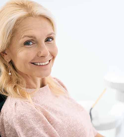 Woman in pink shirt smiling in dental chair