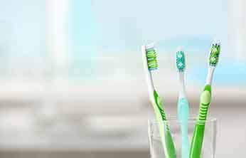 Three toothbrushes in a clear cup