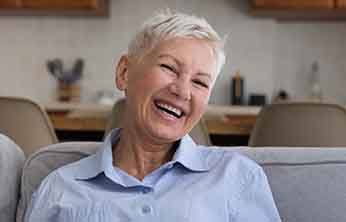 Senior woman sitting on couch and smiling