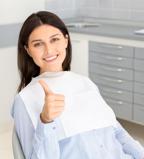 Female dental patient smiling and giving a thumbs up