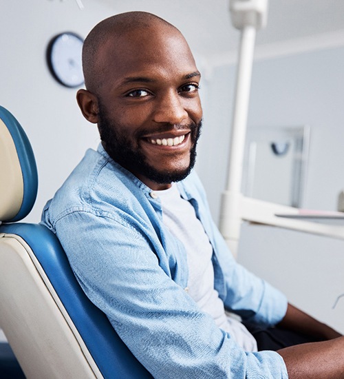 Bearded man sitting in dental chair and smiling