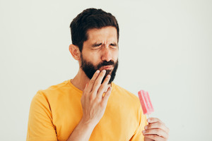 Man with tooth sensitivity after eating a popsicle